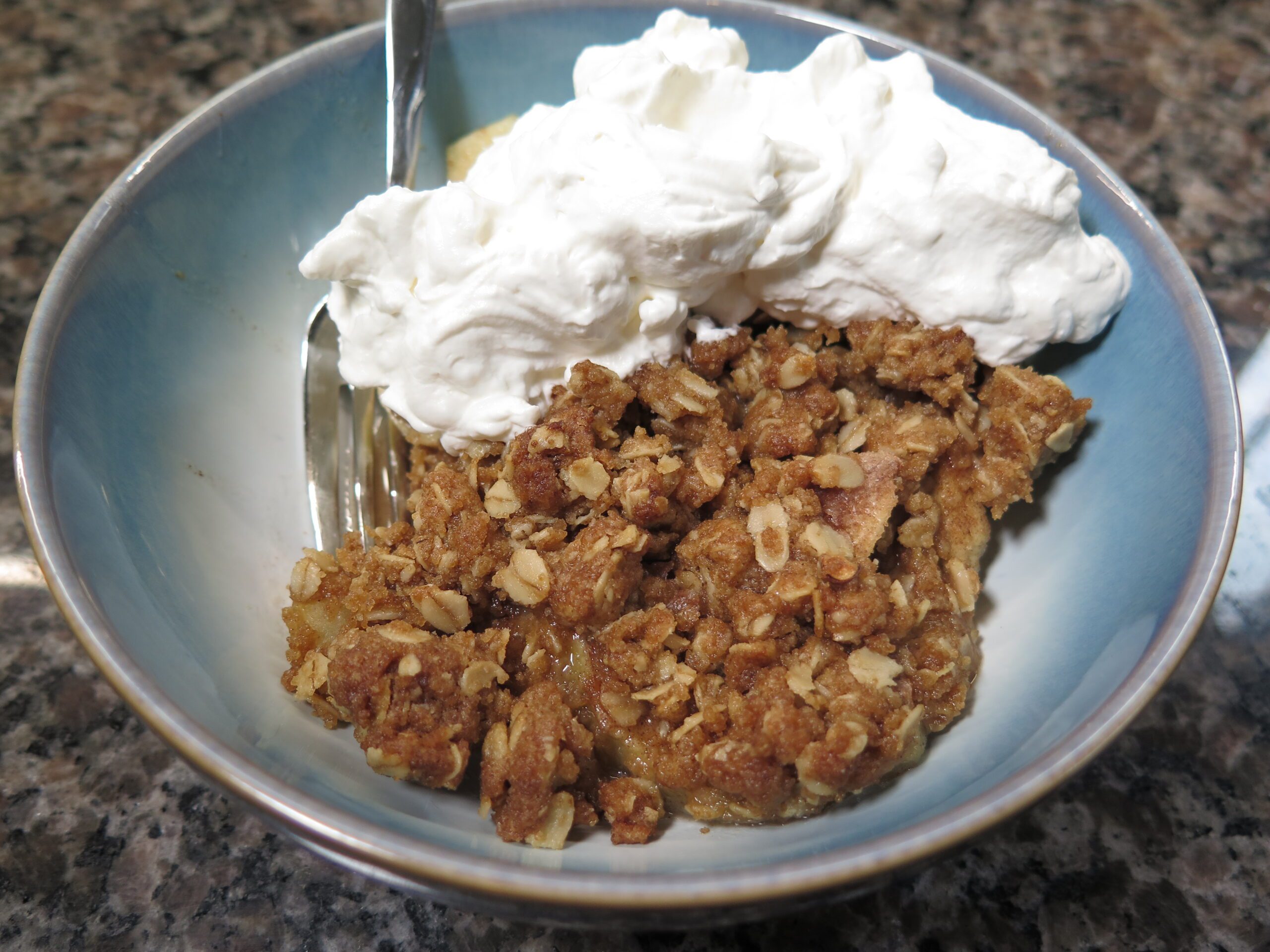Bowl of apple crisp with whipped cream