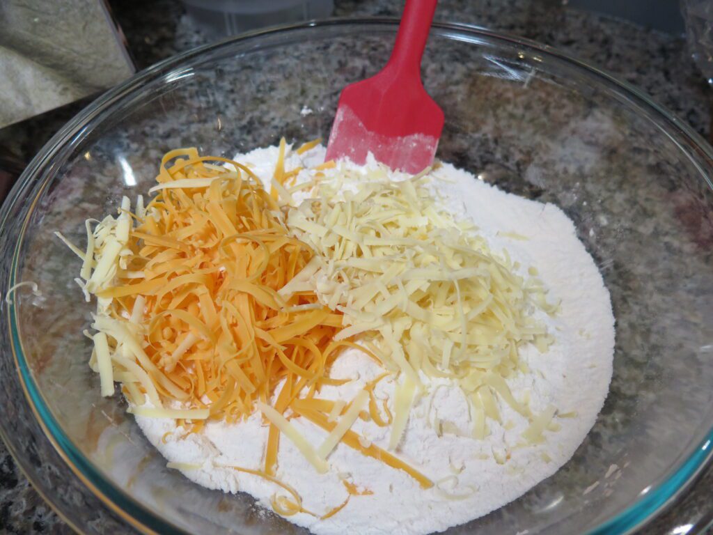 add shredded cheddar cheese to bowl of dry ingredients